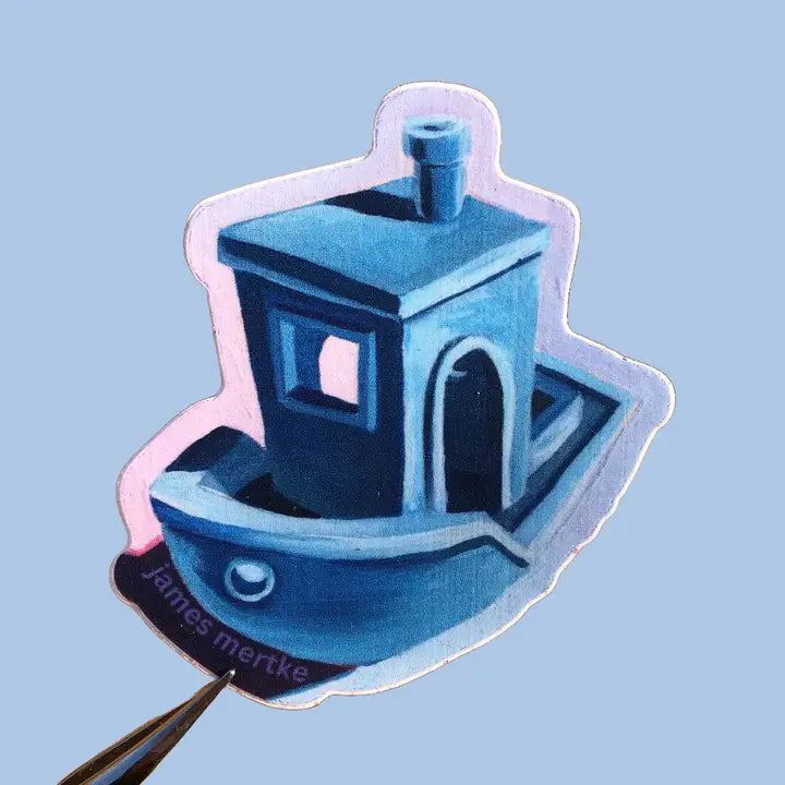 This sticker depicts a painting of Benchy, a blue tugboat used to calibrate a 3D printer.