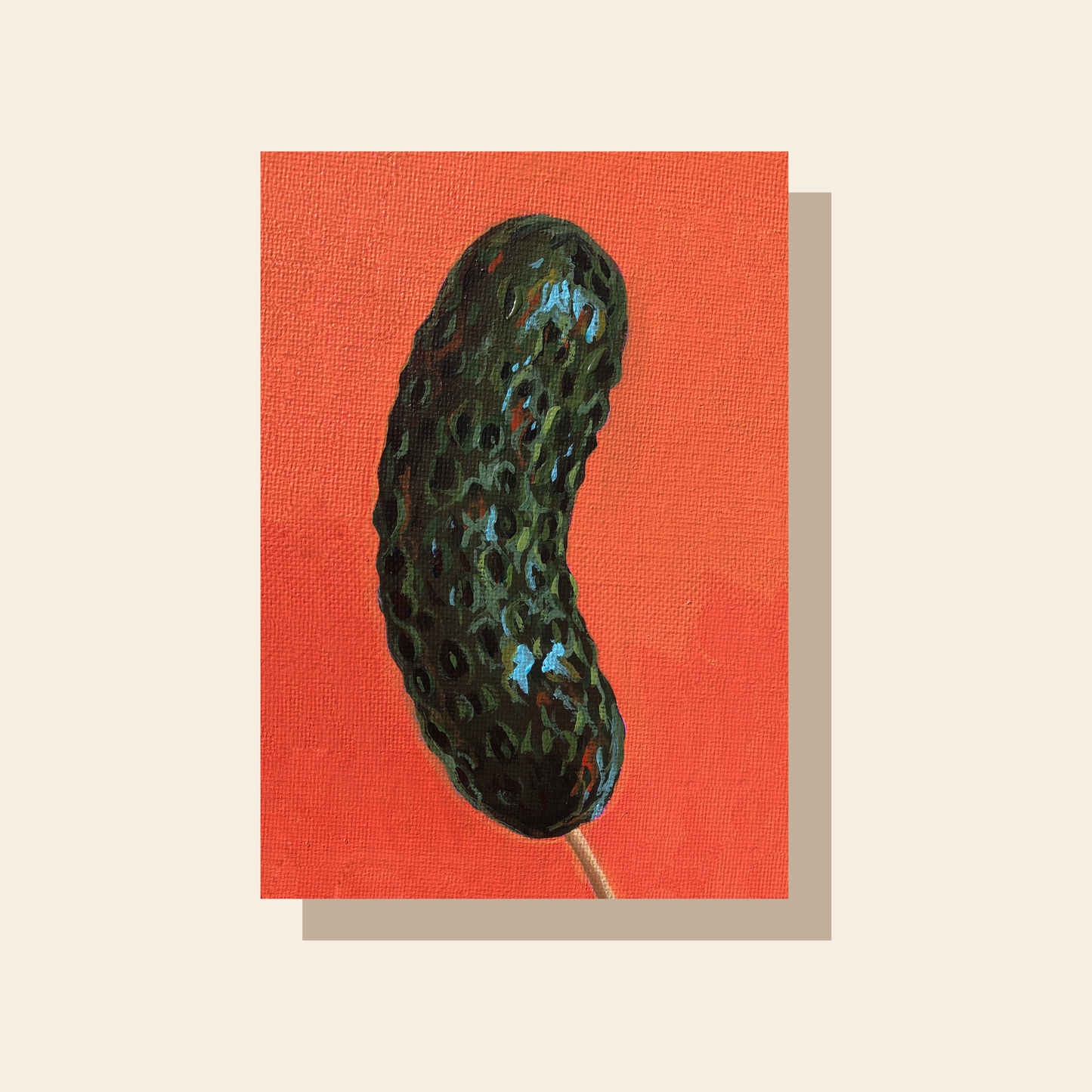 This art print features a glossy dark green pickle on a stick in front of a bright orange background.