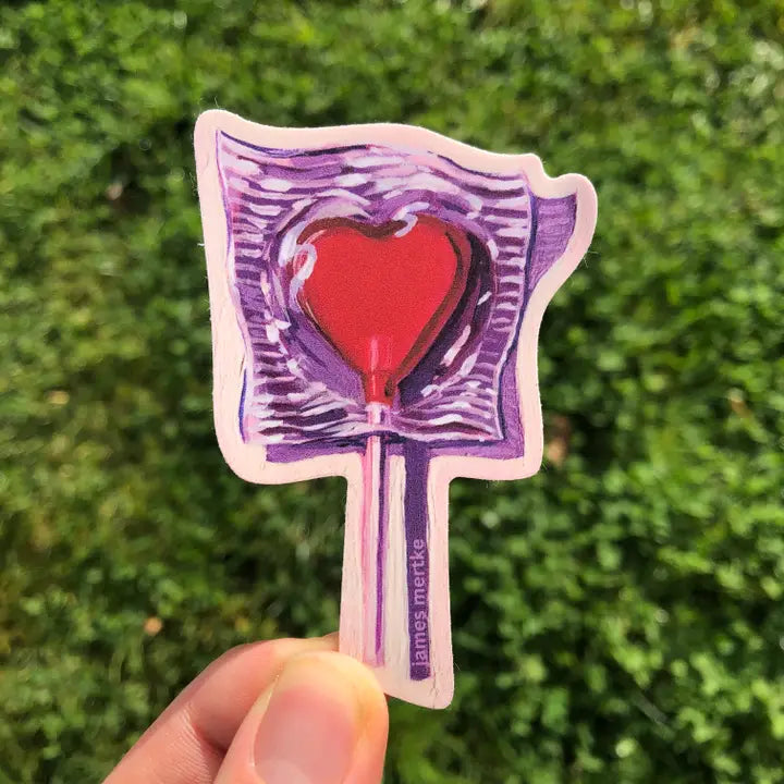 This sticker depicts a painting of a candy heart lollipop. The cany is red and casts a dramatic purple shadow.