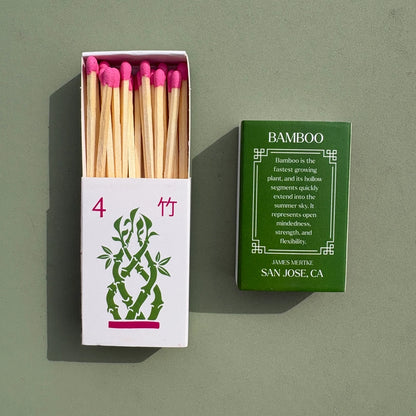 A matchbox is illustrated with a green and pink bamboo to look like a mahjong tile. There is info about the meaning of the plant on the back. Matches with pink heads are inside the box.