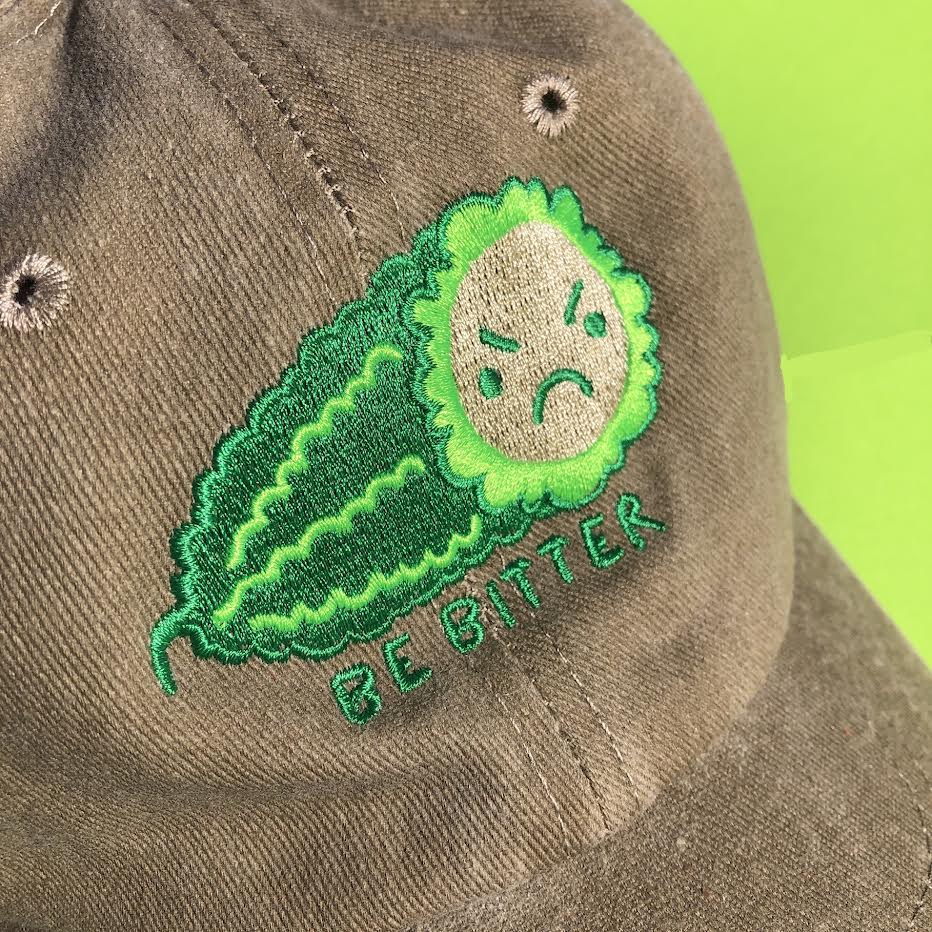 A close up show of the angry bitter melon design. "Be "Bitter" is embroidered underneath on the hat.