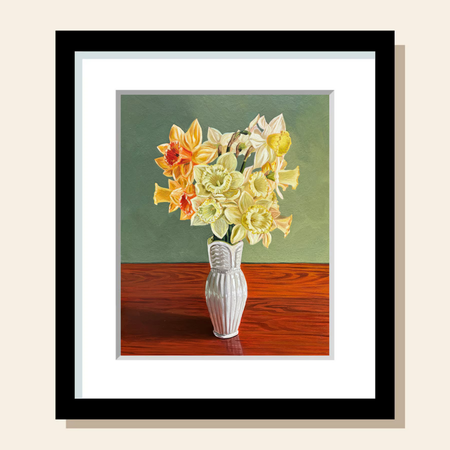 A bouquet of yellow, orange, and white daffodils is gathered in a narrow, white vase. It sits on top of a warm wood grain surface and the wall behind it is a calming green.