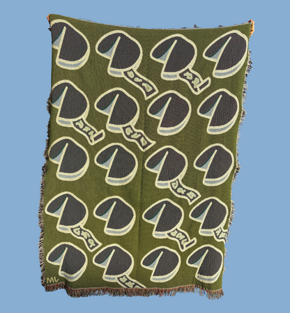 The reverse side of the blanket shows an inverted green pattern of the fortune cookie design. 