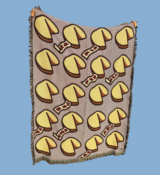 Blanket with fortune cookie pattern. The yellow fortune cookies are on a purple background in the blanket design.