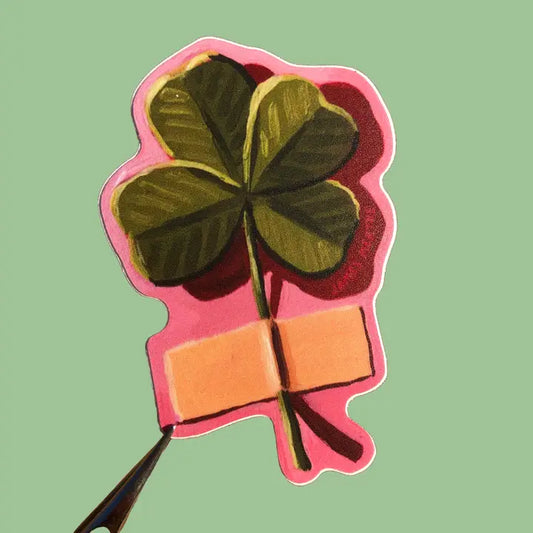 This sticker depicts a painting of a 4 leaf clover stick to the wall with a piece of tape by its stem. It has a pink outline.