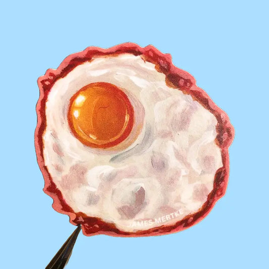 This sticker depicts a painting of a fried egg with a yellow-orange yolk and crispy edges.