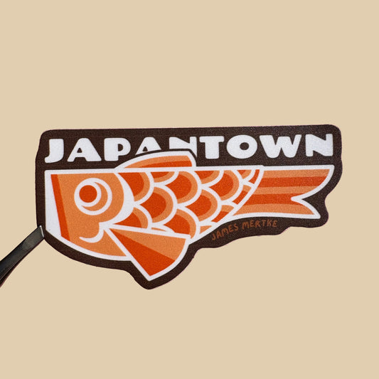 A vinyl sticker featuring an illustration of an orange Japantown Koinobori Carp Kite Sticker on a brown background with "JAPANTOWN" written in a white font above it.