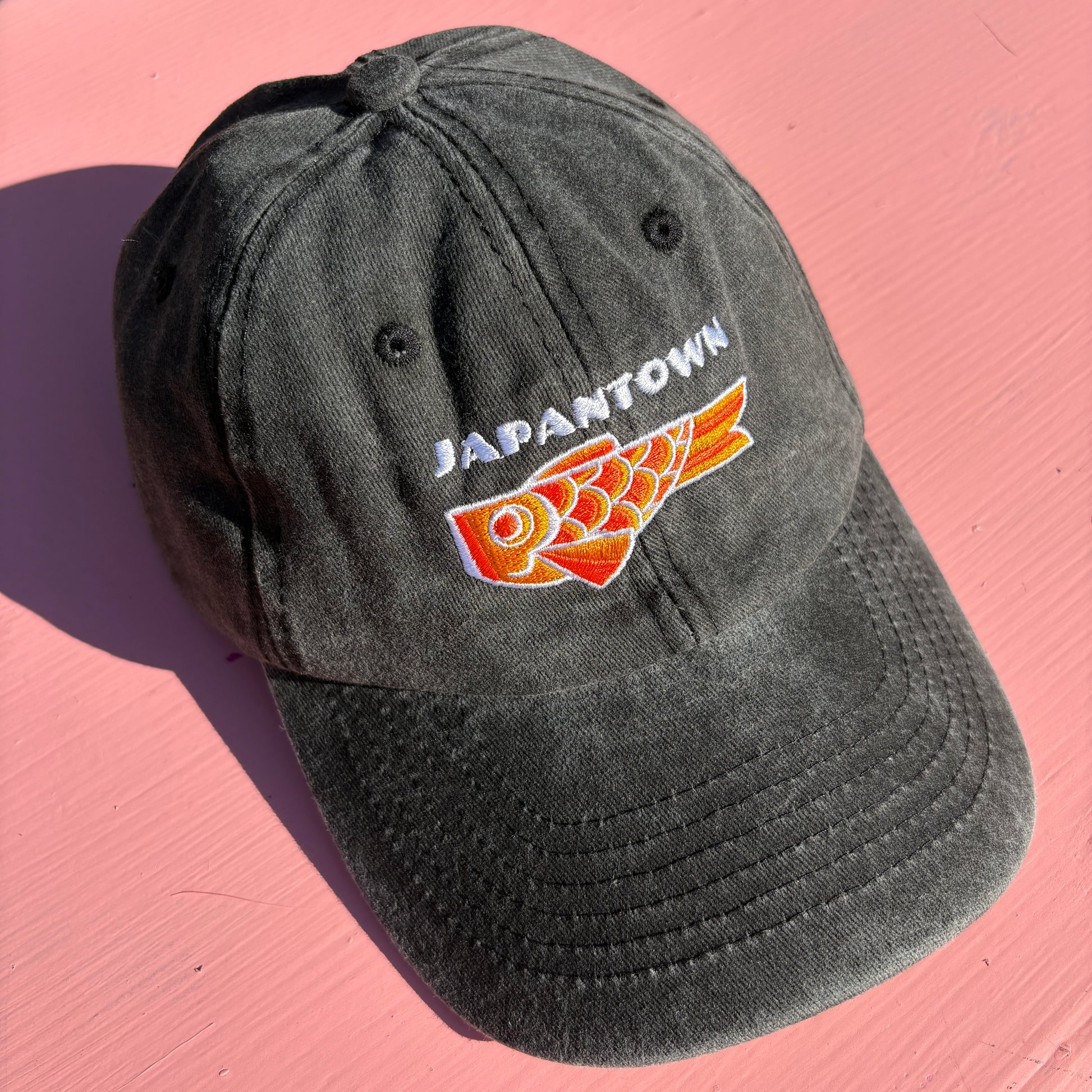 A black washed baseball cap with 'JAPANTOWN' embroidered in white above an orange Koinobori Carp Kite.