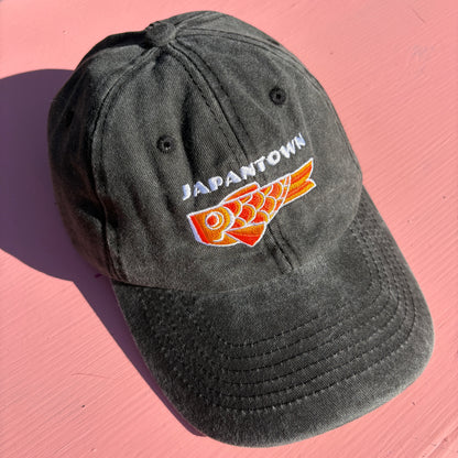 A black washed baseball cap with 'JAPANTOWN' embroidered in white above an orange Koinobori Carp Kite.