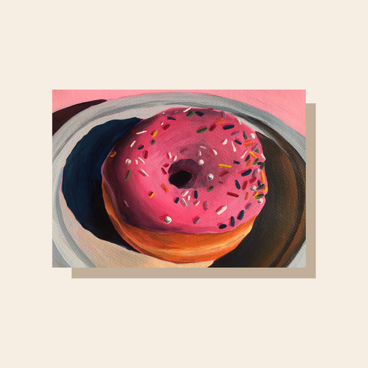 This art print features a painting of a pink sprinkle donut on a plate. The sprinkles are colorful and dramatic shadows are cast y the donut.