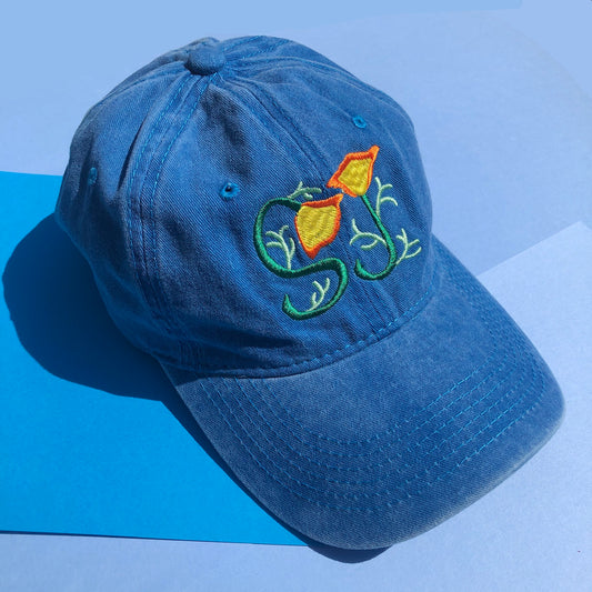 A blue dd hat is embroiled with two California poppies that are curved into the letters "SJ" to represent San Jose, California.