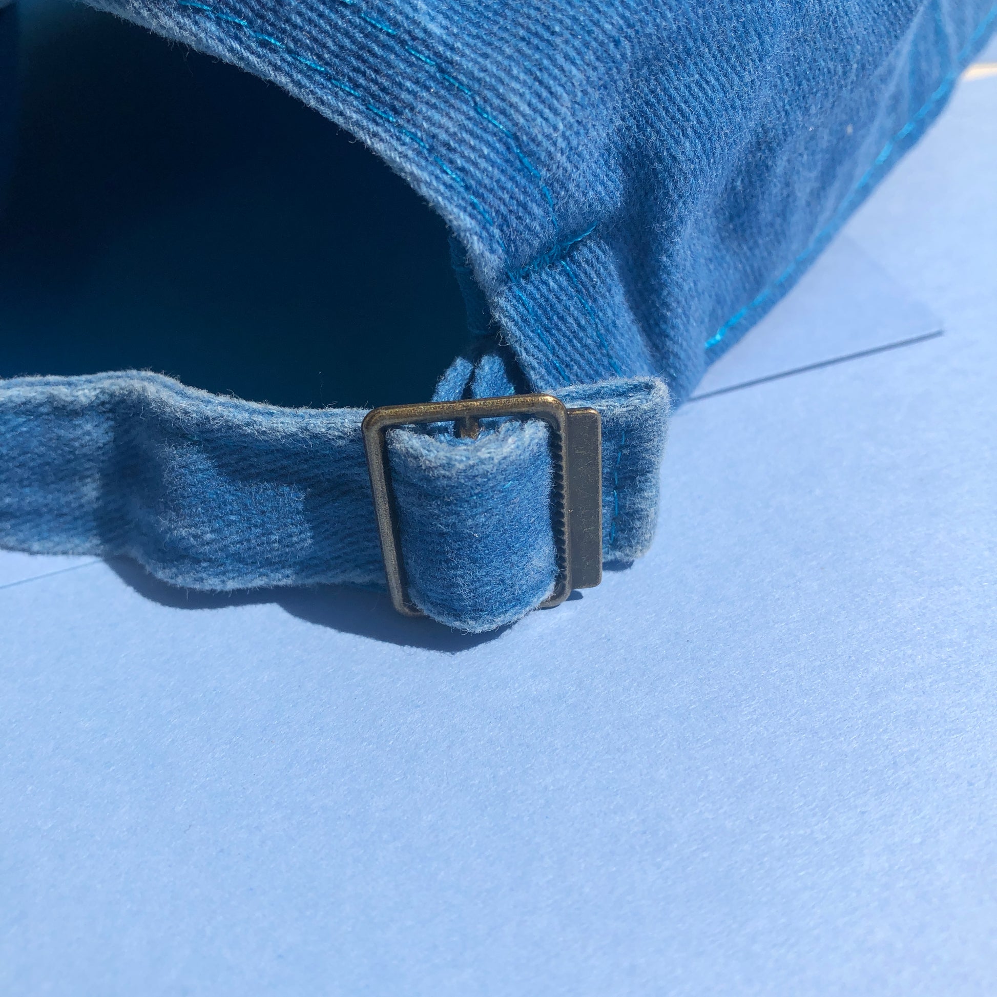 A close up shot of the back of the cap to show the metal buckle that makes the hat adjustable in size.