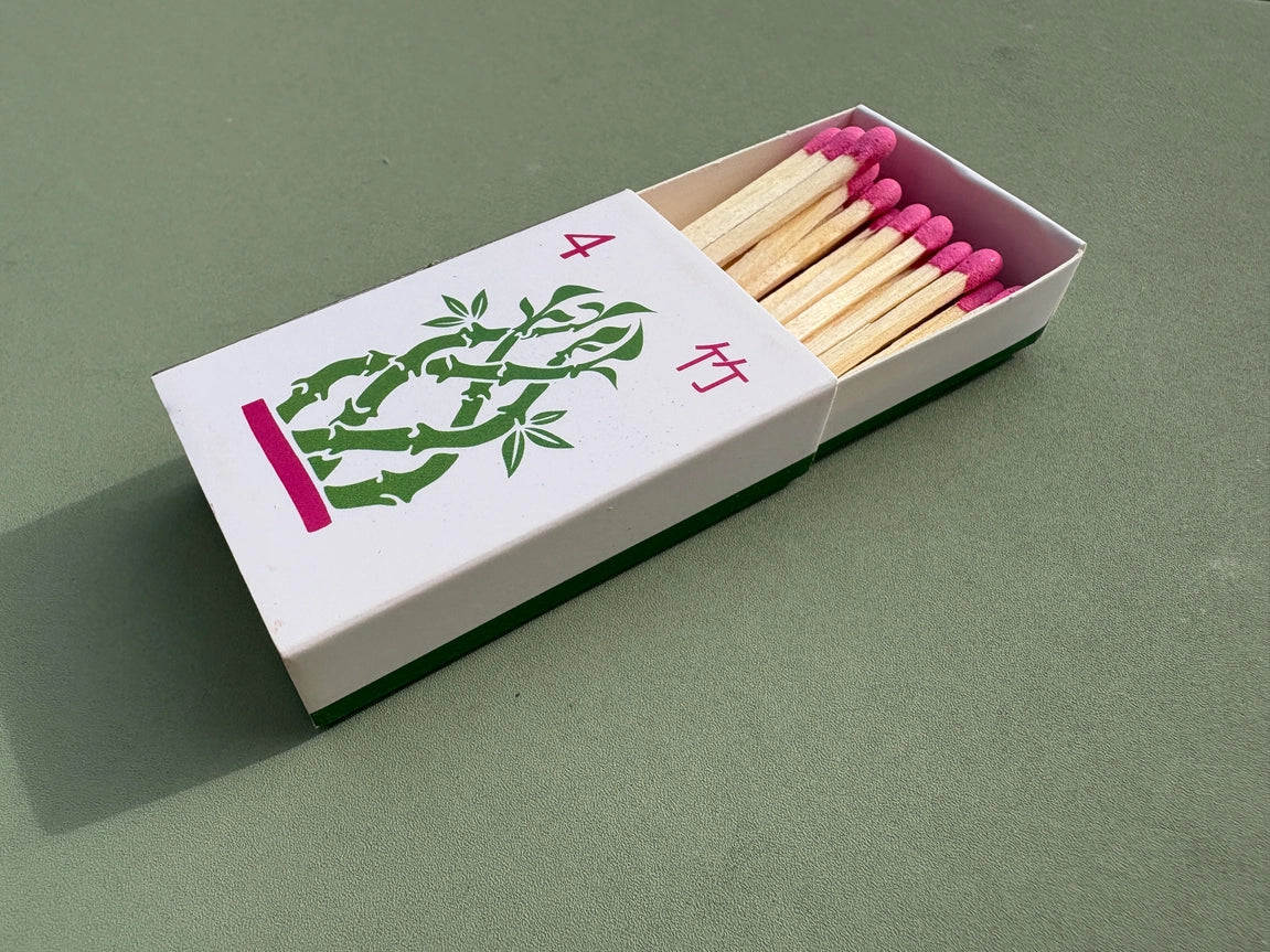 Bamboo matchbox with pink matches on a green background