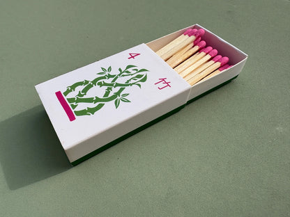 Bamboo matchbox with pink matches on a green background