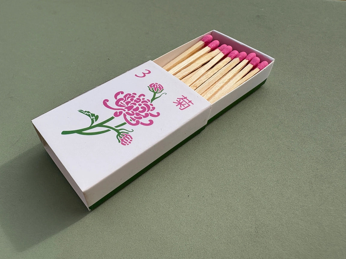 Chrysanthemum matchbox with pink matches on a green background