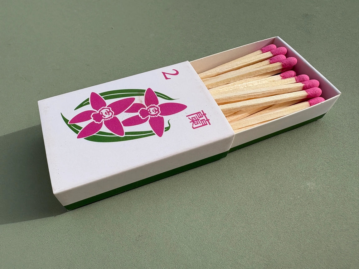 Orchid matchbox with pink matches on a green background