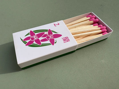 Orchid matchbox with pink matches on a green background