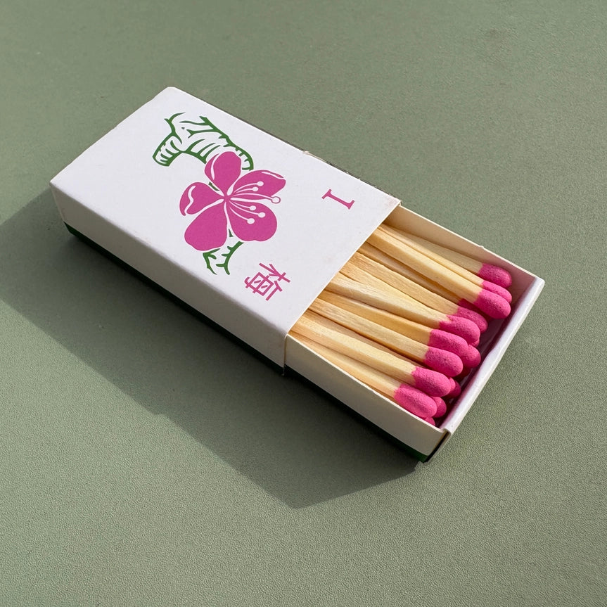 Plum blossom matchbox with pink matches on a green background