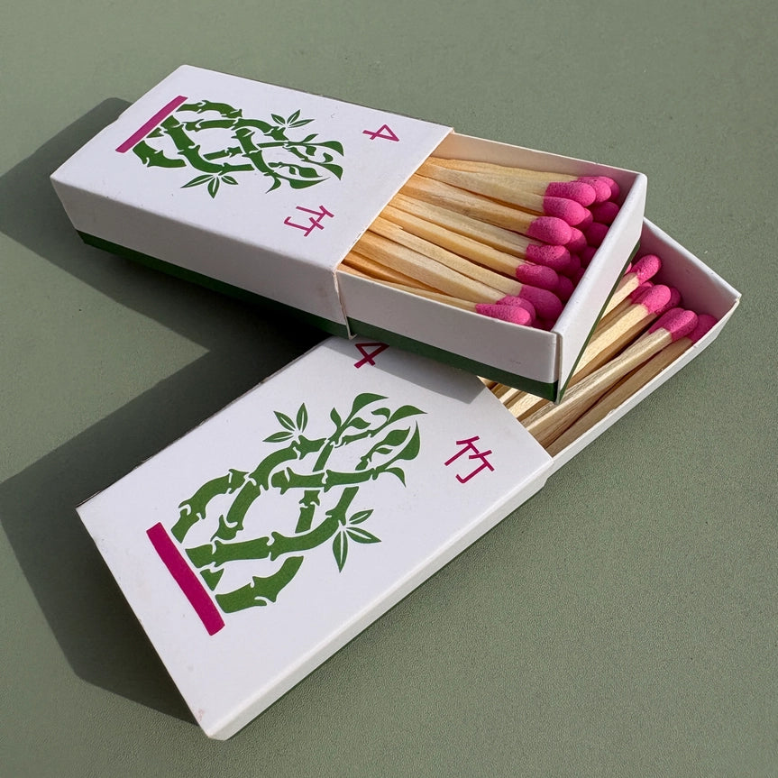 Bamboo matchbox with pink matches and floral design on a green background