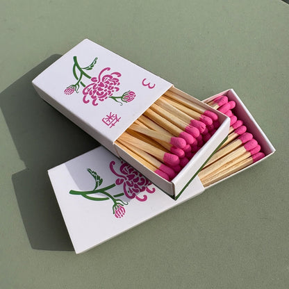 Chrysanthemum matchbox with pink matches and floral design on a green background
