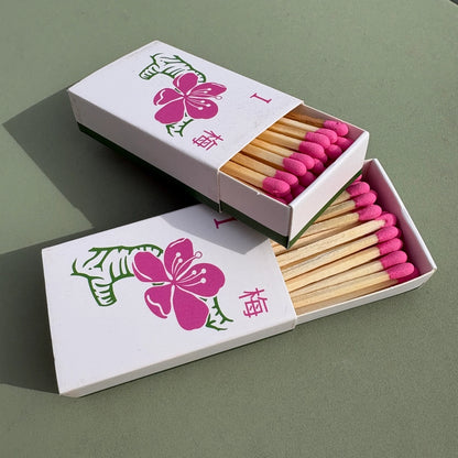Plum blossom matchbox with pink matches and floral design on a green background