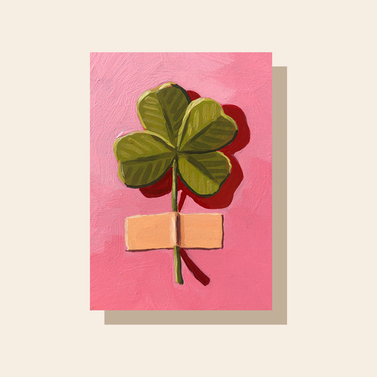 This art print features a green 4 leave flower taped vertically onto a bright pink surface.