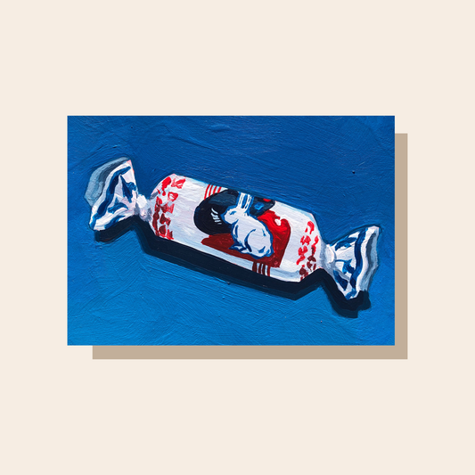 This painting features a white rabbit candy on a dark blue background. The white, black, blue, and red wrapper of the candy features different patterns and a bunny on the front.