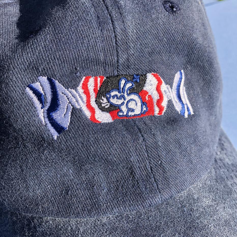 A close up shot of the embroidered white rabbit candy design on the dark blue hat.